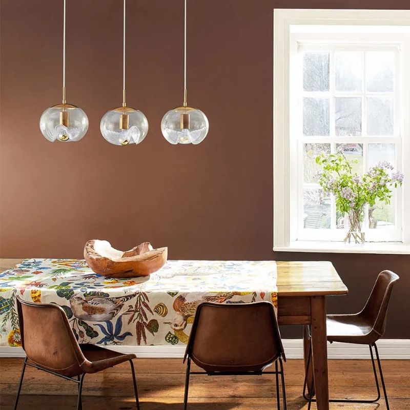 Benjamin Moore Leather Saddle Brown, a color trend 2025 paint color in a dining room with white trim and warm accents